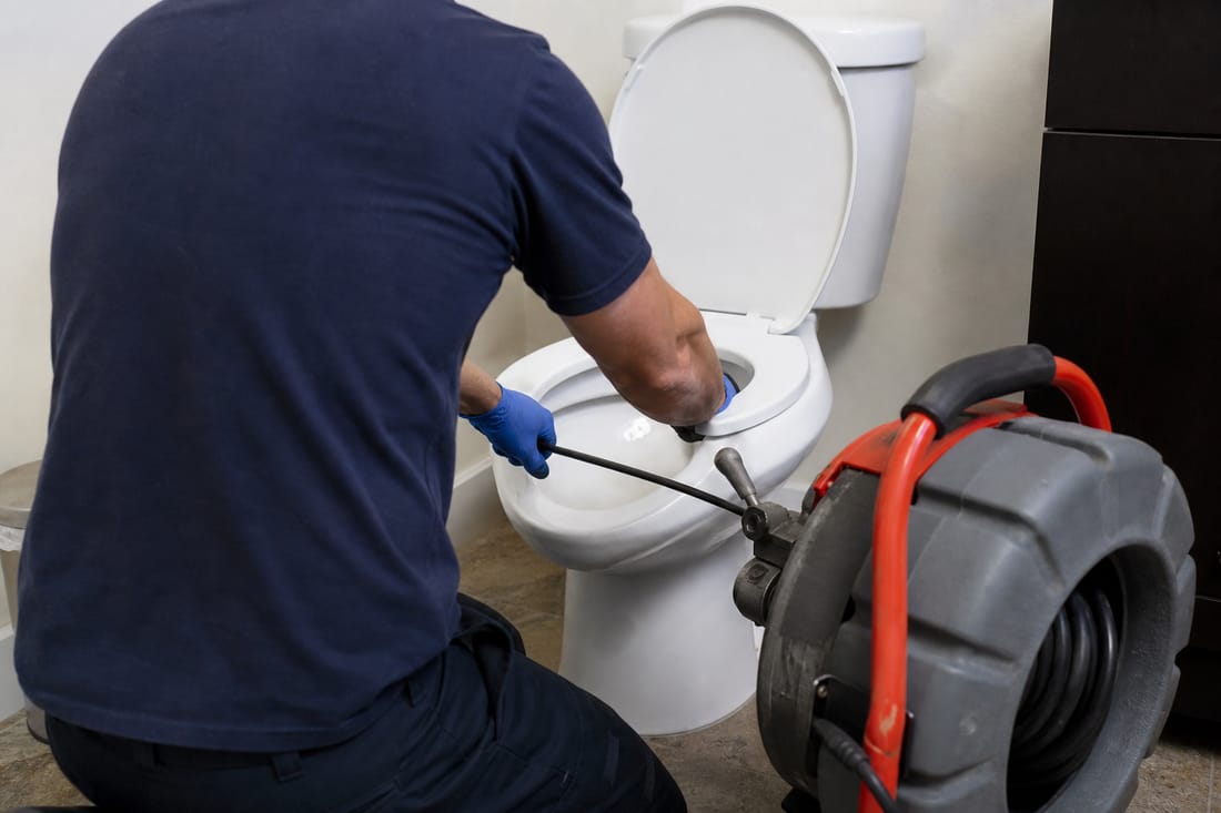 Beispiel: Techniker entstopft ein WC von hinten